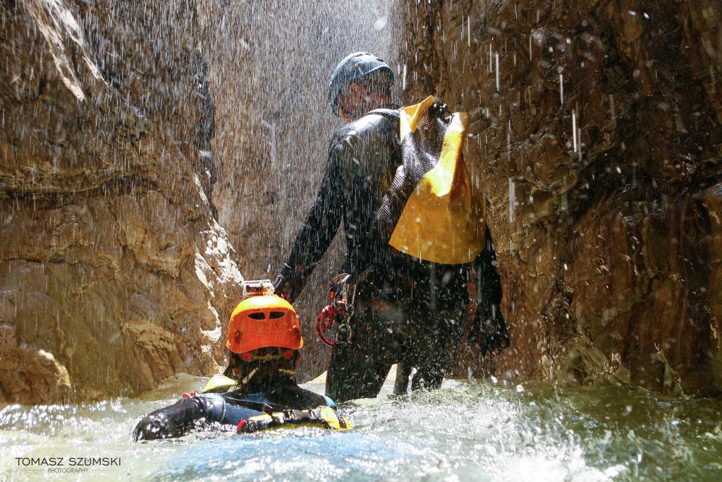 Sylwetki osób w kanionie w kaskach i uprzężach